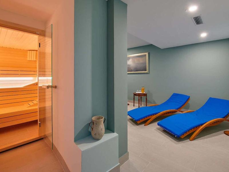 Nowoczesna strefa wellness z sauną i niebieskimi leżakami w spokojnym otoczeniu.