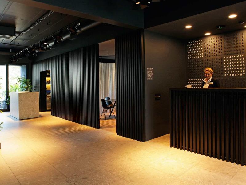 Moderner Empfangsbereich mit dunklen Wänden, hellem Boden und indirekter Beleuchtung.