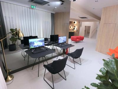 Spazio di lavoro moderno con tavoli, sedie e computer in una stanza luminosa con parete a specchio.