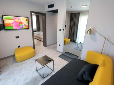 Modern hotel room with yellow seating and flat-screen TV.