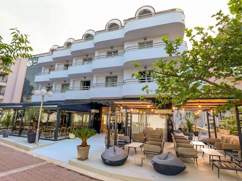 Modern hotel building with multiple floors and outdoor seating areas on a cloudy day.