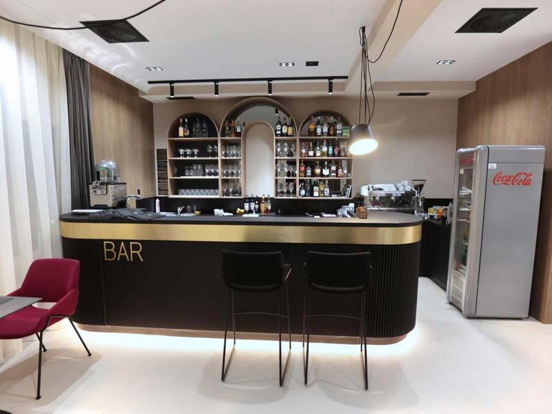 Modern hotel bar with black counter, gold accents, and two bar stools.