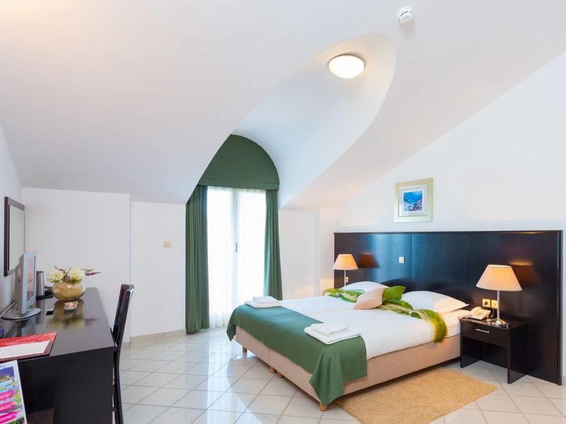 Modern hotel room with double bed, green curtain, and desk