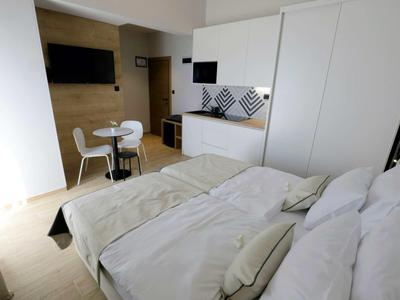 Camera d'hotel moderna con letto matrimoniale, tavolo da pranzo e angolo cottura.