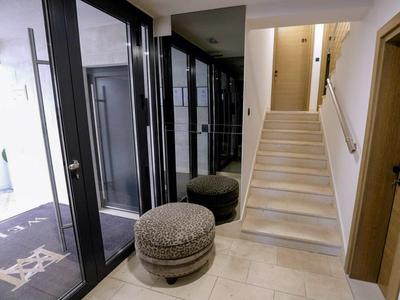 Modern hotel corridor with stairs and cozy round stools beside glass walls.