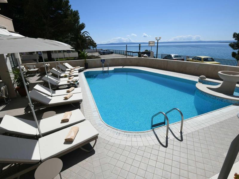Piscina dell'hotel con lettini e vista mare sotto cielo limpido