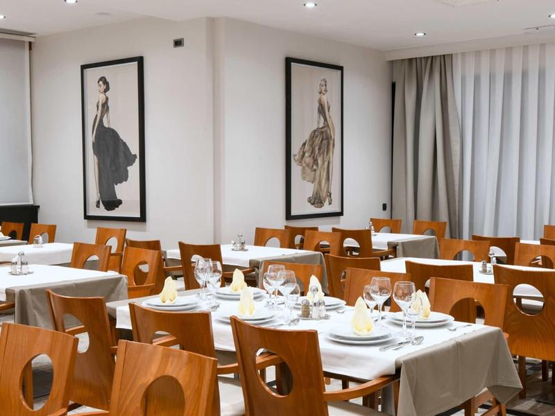 Sala da pranzo moderna con eleganti tavoli e sedie in legno apparecchiati per gli ospiti.