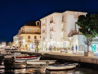 Hotel iluminado junto al agua con botes a lo largo de la orilla por la noche