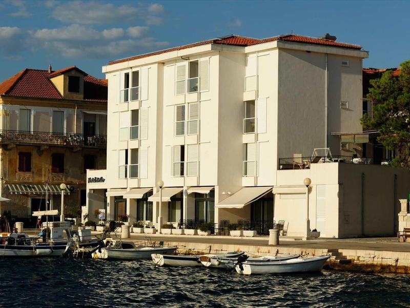 Edificio moderno bianco dell'hotel sull'acqua con barche in primo piano in una giornata di sole.