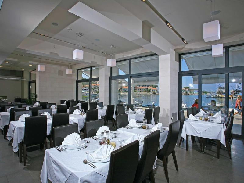 Ristorante moderno con tavoli coperti di bianco e vista sull'acqua.