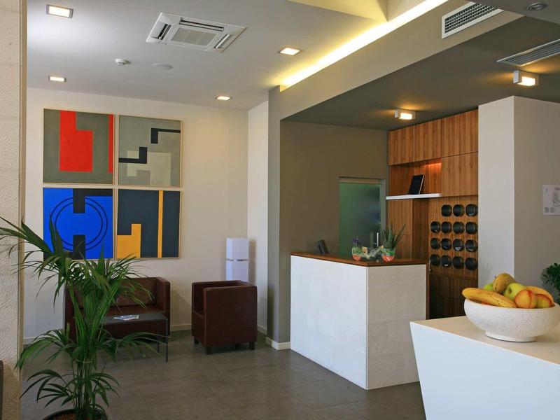 Area hall dell'hotel moderna con reception, arte murale e piante decorative.