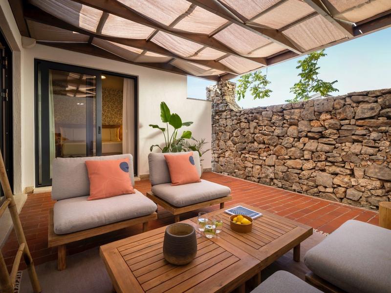 Cozy terrace with wooden furniture and stone wall, perfect for relaxed vacation moments.