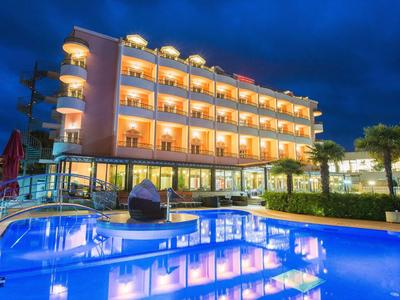 Hôtel moderne de nuit avec piscine éclairée et chambres avec balcon.