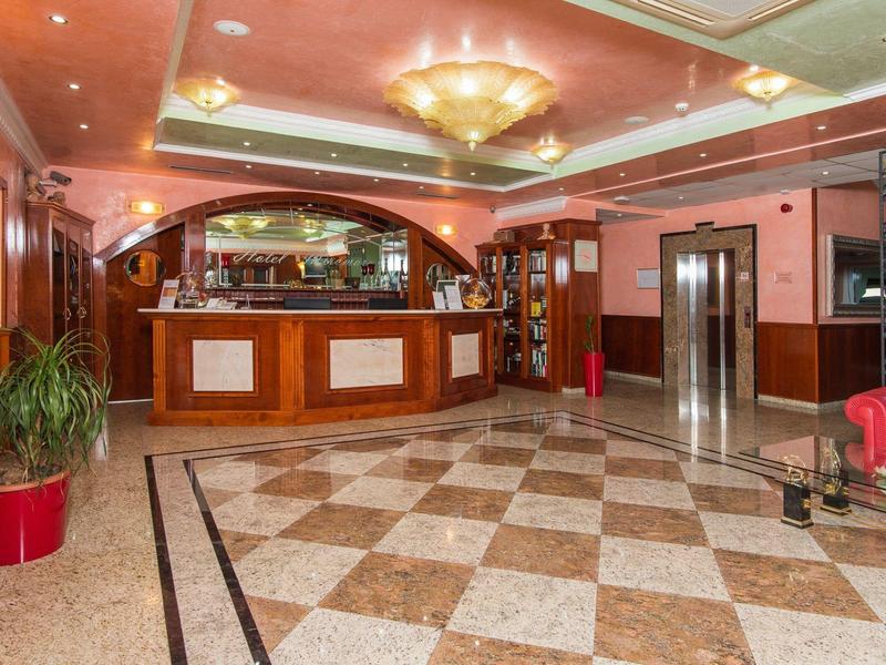 Heller Hotellobby mit Rezeption, Aufzug und dekorativen Pflanzen