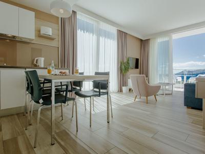 Bright vacation apartment with kitchenette, dining table, and panoramic windows with mountain view.