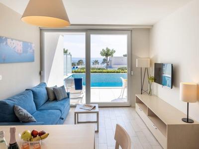 Cozy living room with blue sofa and view of private pool and terrace.