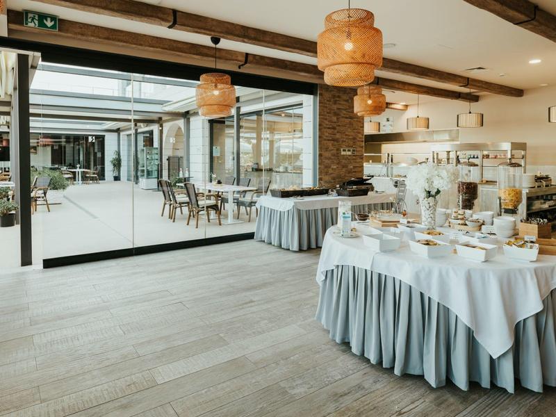 Bright indoor dining area with set tables and a view of an outdoor terrace.