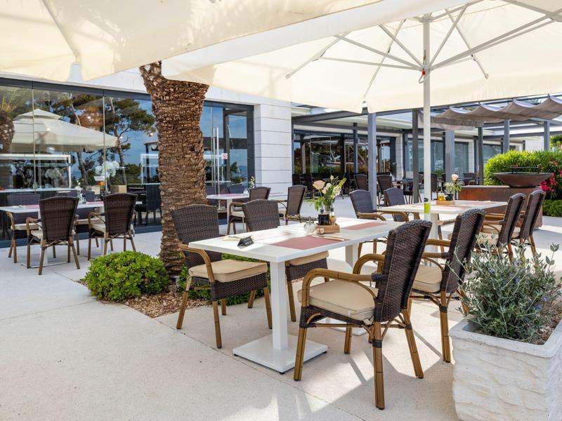 Outdoor seating area of a hotel with tables, chairs, and large umbrellas.