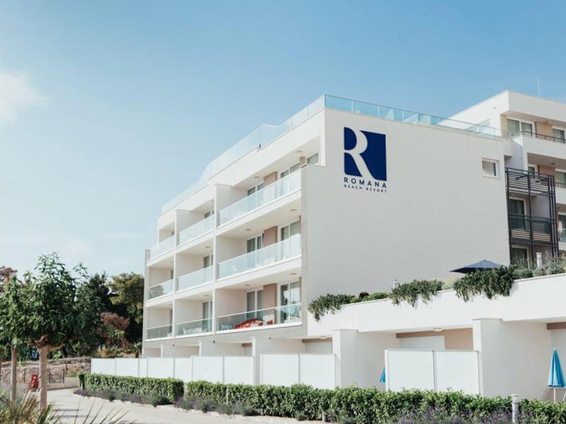 Modern multi-story hotel building with balconies and blue sky in the background.