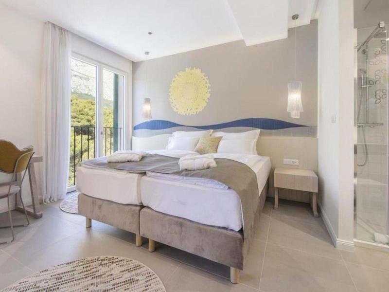 Nowoczesny pokój hotelowy z łóżkiem podwójnym, balkonem i jasnym wnętrzem.