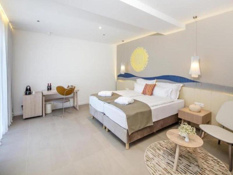 Nowocześnie urządzone pokoje hotelowe z łóżkiem podwójnym, telewizorem i częścią wypoczynkową.