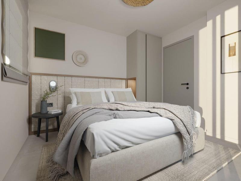 Světlá ložnice s manželskou postelí, šedým povlečením a malým nočním stolkem u okna.