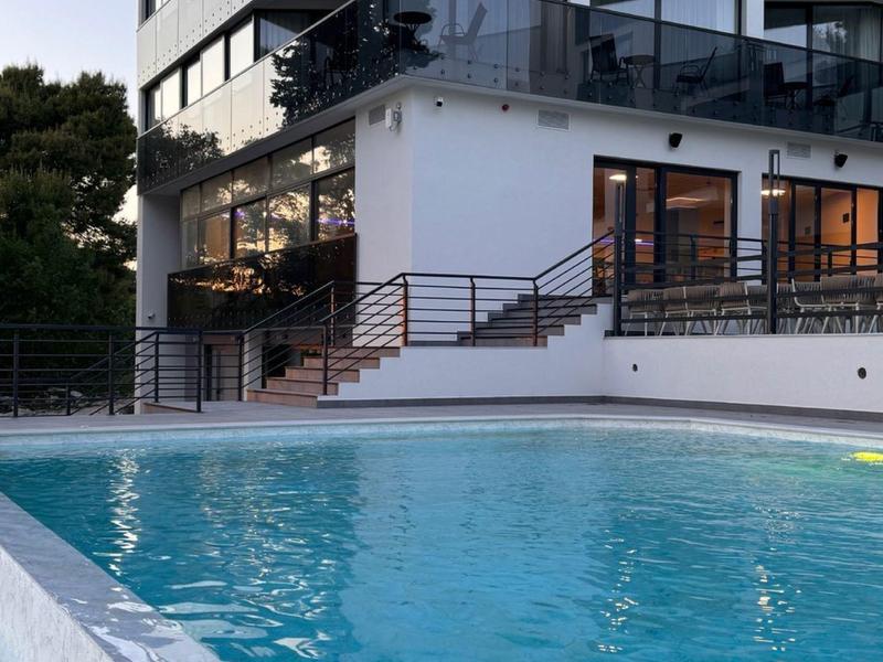 Nowoczesny kompleks hotelowy z oświetlonym basenem wieczorem.