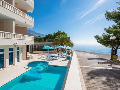 Hotel mit Pool und Jacuzzi, Sonnenschirmen, Aussicht aufs Meer und blauem Himmel.