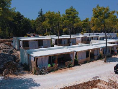 Modern flat holiday homes with white facades set in a wooded area.