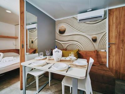 Cozy dining area with table, chairs, and sofa bench in a modern hotel room.