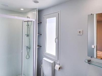 Bright bathroom with shower, toilet, sink, and towel hanging on the wall.