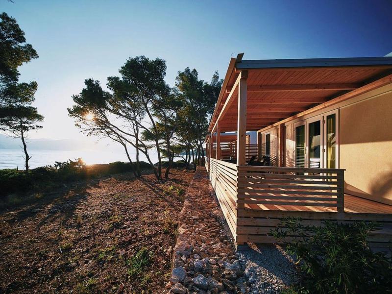 Modern bungalow with wooden balcony by the sea in a calm, wooded setting