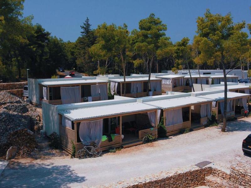 Modern flat holiday homes with white facades set in a wooded area.