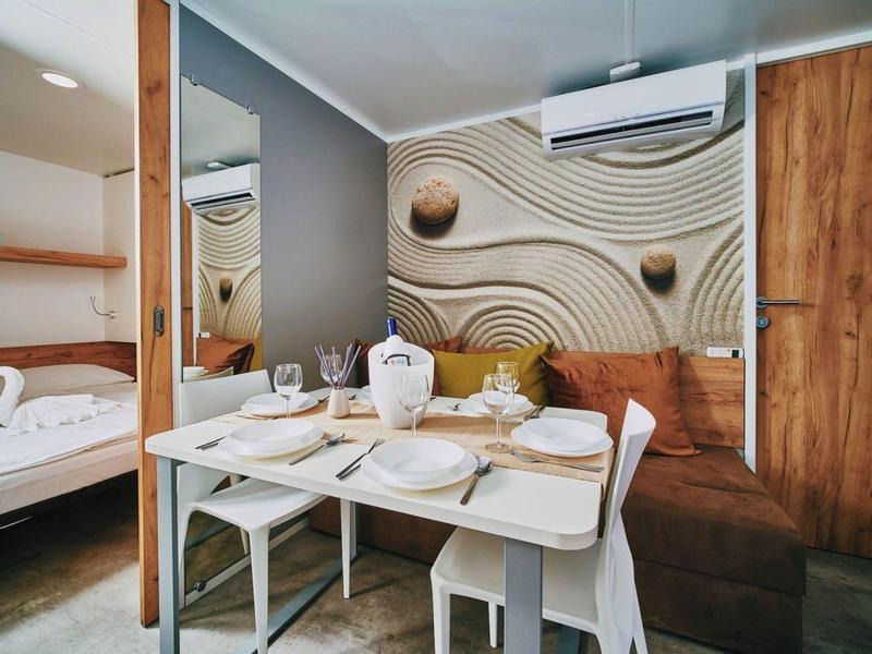 Cozy dining area with table, chairs, and sofa bench in a modern hotel room.