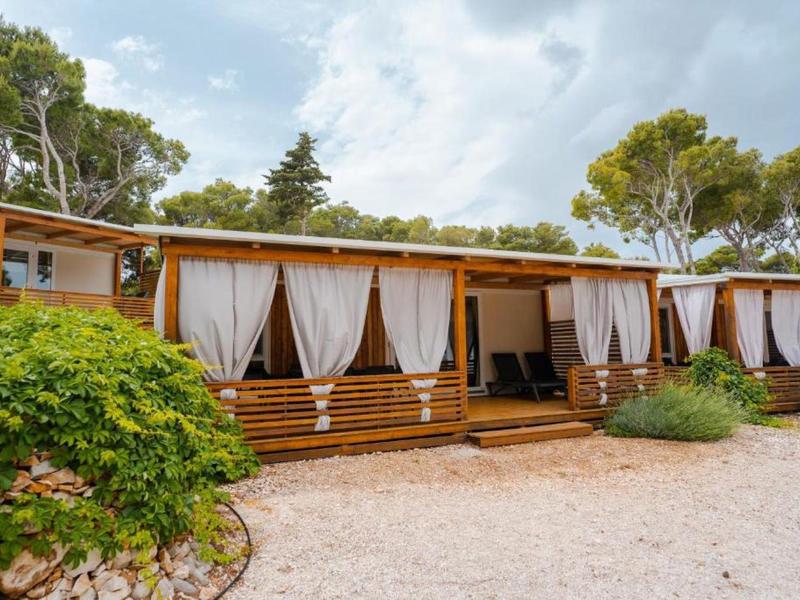 Wooden terrace with white curtains at a hotel surrounded by trees and plants.