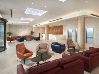 Moderne Hotellobby mit Ledersesseln, Sofas und hellem, minimalistischen Design.