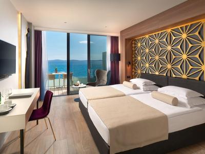 Nowoczesny pokój hotelowy z dwoma łóżkami, widokiem na morze i balkonem z krzesłami