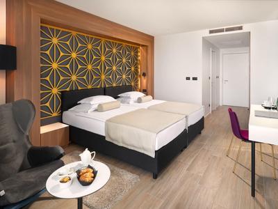 Nowoczesny pokój hotelowy z dwoma pojedynczymi łóżkami, dekoracyjnym zagłówkiem i biurkiem