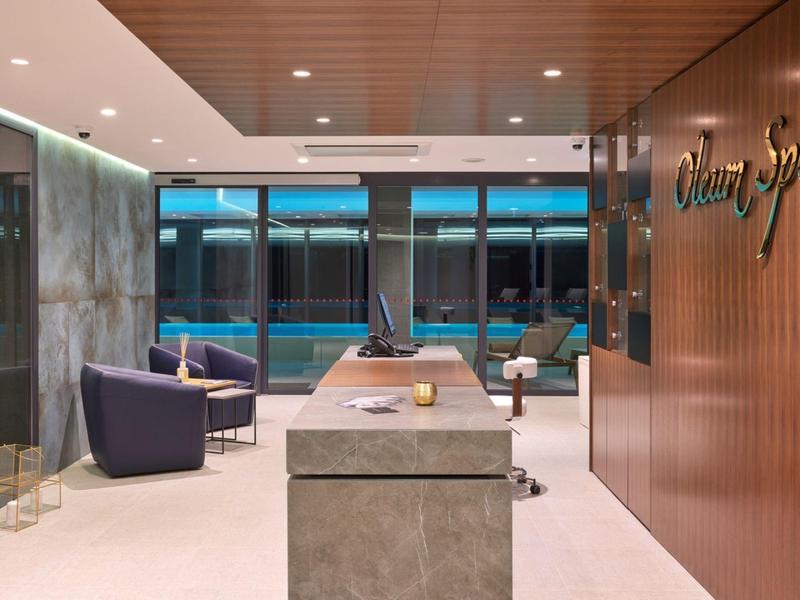 Nowoczesny recepcja spa z meblami wypoczynkowymi i panoramicznym widokiem na basen.