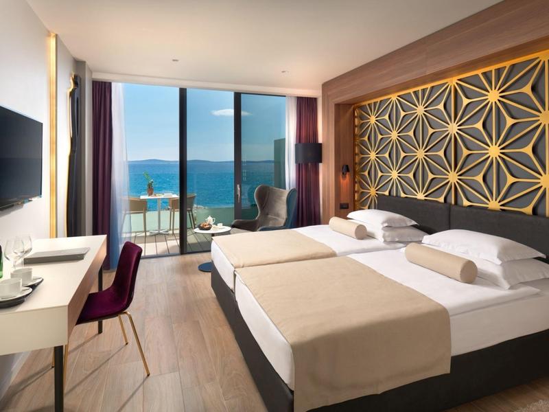 Nowoczesny pokój hotelowy z dwoma łóżkami, widokiem na morze i balkonem z krzesłami