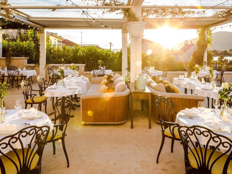 Jasna restauracja oświetlona słońcem z eleganckimi krzesłami i artystycznie nakrytymi stołami.