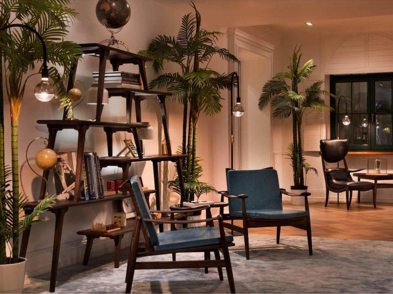 Przytulny hotelowy salon z drewnianymi krzesłami, roślinami i ciepłym oświetleniem