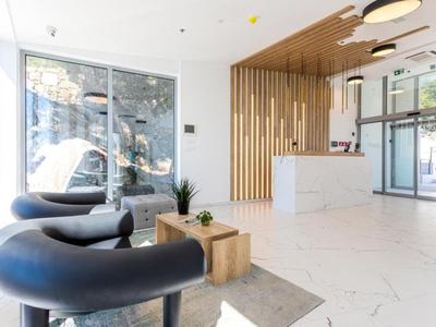 Bright hotel lobby with seating area and wooden reception desk.