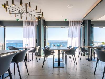 Modern hotel restaurant with sea view, minimalist furniture, and large windows.