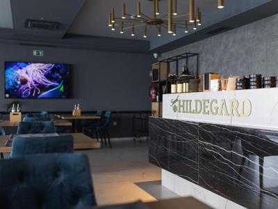 Modern hotel bar with marble front, blue chairs, and large TV on the wall.