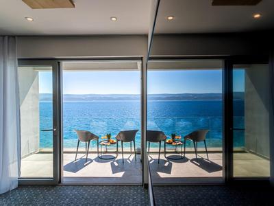 Balkon mit Stühlen und Tisch mit Blick auf das Meer an einem sonnigen Tag.