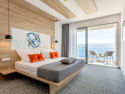 Modernes Hotelzimmer mit Doppelbett und Balkon mit Meerblick.