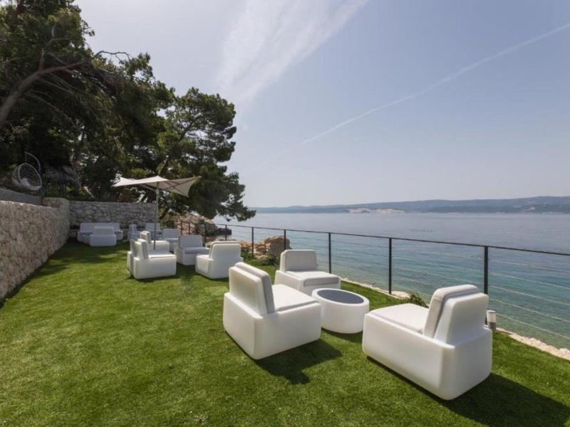 Moderne Sitzgruppe auf einer Rasenfläche mit Blick aufs Meer und blauen Himmel.