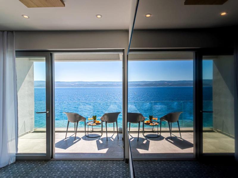Balkon mit Stühlen und Tisch mit Blick auf das Meer an einem sonnigen Tag.