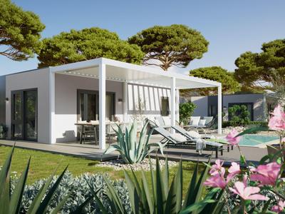 Modernes weißes Ferienhaus mit Terrasse, Liegestühlen und Pool, umgeben von Bäumen und Blumen.